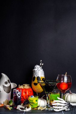 Cadılar Bayramı partisinin şenlik içeceği, çeşitli renkli içkiler, alkolsüz kokteyller, Cadılar Bayramı karakterleriyle içkiler, kostümler, tatil dekorları ve semboller.