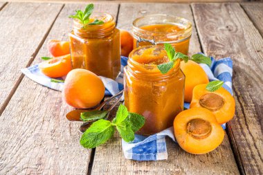 Farklı kavanozlarda ev yapımı kayısı reçeli, ahşap arka planda taze organik kayısılar fotokopi alanı