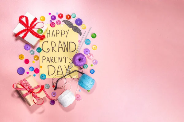 Happy Grandparents day greeting card background. Granny and grandpa\'s day celebration, with gift boxes, knitting threads, buttons, glasses, decor top view copy space