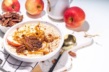 Basit bir sonbahar geleneksel Amerikan kahvaltısı. Elmalı yulaflı yulaf lapası, elmalı, cevizli ve karamelli beyaz masa arkası fotokopi masası.