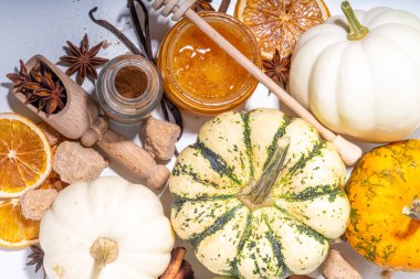 Sonbahar mevsimi balkabağı baharat pişirme ve içecekleri içme. Çeşitli renkli balkabakları, fındıklar, beyaz arka planda mevsimlik baharatlar. Balkabağı turtası, latte, sonbahar Şükran Günü için kurabiyeler.