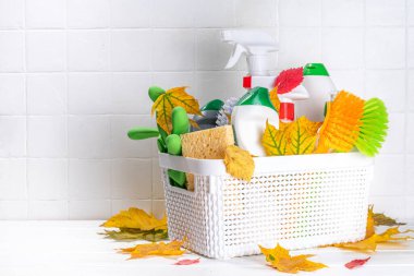 Sonbahar temizliği, sonbahar temizlik kampanyası için reklam afişi. Çeşitli deterjanlar, şişeler, sprey, aksesuarlar, çatallar, sonbahar yaprakları ve dekoru olan beyaz ahşap arka plan.