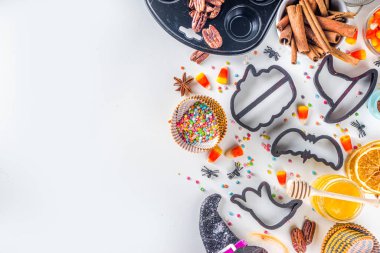Cadılar Bayramı zencefilli kurabiye pişirme arka planı. Sonbahar tatili pişirme konsepti, malzemeler, baharatlar, cadılar bayramı sembolü kurabiye kesiciler - balkabağı, hayalet, yarasa, cadı şapkası, üst görünüm beyaz masa kopyalama alanı