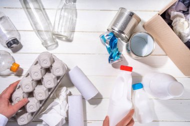 Çöp ayıklama, atık geri dönüşüm konsepti. Geri dönüşüm malzemelerinin olduğu kutu - plastik, cam, kağıt, karton, beyaz ahşap arka plan fotokopi alanı. Kadın elleri çeşitli çöp ve çöpleri ayırıyor.