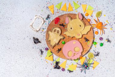 Funny halloween sandwiches. Set of various decorated symbols sandwich - bat, skull, ghost, with cucumber, cheese and meat sausages, white table background with Halloween decorations