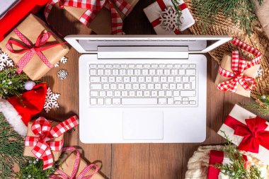 Üzerinde Noel hediyesi kutuları olan dizüstü bilgisayar tahta arka planda. Hediyeli defter, köknar ağacı ve kış dekoru. Noel ve Yeni Yıl için Hazırlık
