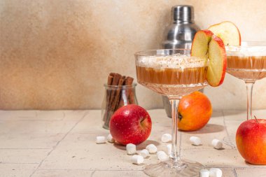 Elmalı marshmallow kokteyli, sonbahar baharatları ve marşmelovlu lezzetli elma suyu martini, bej arka planda taze elma.