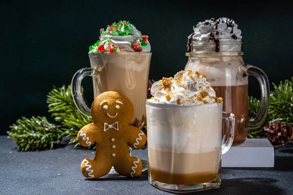 Autumn winter coffee latte set, Autumn winter coffee drink assortment with various topping - gingerbread caramel, mocha chocolate, candy cane peppermint latte in different cups, over dark background
