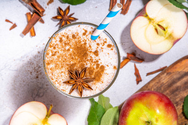 Apple pie smoothie with yogurt, apple slices, oatmeal granola flakes, cinnamon, spices and walnuts. Healthy uatumn breakfast or snack, with fresh raw apples and spices copy space