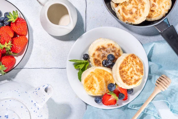 stock image Cottage cheese pancakes, syrniki with fresh berries, sweet summer breakfast. Pan fried roasted portioned cheesecakes 