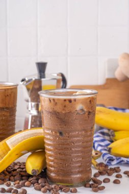 Karışık muzlu kahve. Soğuk latte kahve ve muzsuz süt, vejetaryen diyet içecek, donmuş muz ve espresso, beyaz mutfak masasında fotokopi alanı.