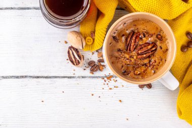 Sonbahar kış baharatlı içecek, Akçaağaç fındık kahve fincanı beyaz ahşap masa üzerinde sıcak süveter ve malzemeler yer kopyalayabilir.