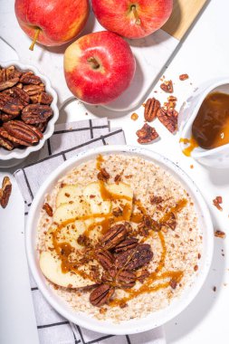 Basit bir sonbahar geleneksel Amerikan kahvaltısı. Elmalı yulaflı yulaf lapası, elmalı, cevizli ve karamelli beyaz masa arkası fotokopi masası.