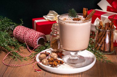 Yeni yıl Noel kremalı baharatlı kokteyl Eggnog, Cola Demosu. Sütlü, yumurtalı, romlu, tarçınlı ve hindistan cevizli sıcak kış içeceği ahşap arka planda Noel süsüyle