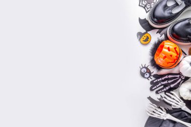 Çocukların Cadılar Bayramı partisi için hazırlıklar, şeker mi şaka mı geleneği. Geleneksel çocuk Cadılar Bayramı kostümlü cadı, hayalet, iskelet, balkabağı aksesuarları, şeker kovası, beyaz arka planda dekor.