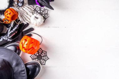 Çocukların Cadılar Bayramı partisi için hazırlıklar, şeker mi şaka mı geleneği. Geleneksel çocuk Cadılar Bayramı kostümlü cadı, hayalet, iskelet, balkabağı aksesuarları, şeker kovası, beyaz arka planda dekor.