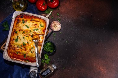 Homemade cannelloni pasta, big tray with baked cannelloni with minced meat with bechamel sauce,with herbs in ingredient on dark background