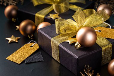 Mutlu Noeller, mutlu bayramlar tebrik kartı geçmişi, yeni yıl, Noel, kış xmas tatilleri düzlüğü. Noel altın süsleri, dekor köknar ağacı, siyah arkaplandaki hediye kutuları, fotokopi alanı