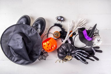 Çocukların Cadılar Bayramı partisi için hazırlıklar, şeker mi şaka mı geleneği. Geleneksel çocuk Cadılar Bayramı kostümlü cadı, hayalet, iskelet, balkabağı aksesuarları, şeker kovası, beyaz arka planda dekor.