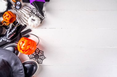 Çocukların Cadılar Bayramı partisi için hazırlıklar, şeker mi şaka mı geleneği. Geleneksel çocuk Cadılar Bayramı kostümlü cadı, hayalet, iskelet, balkabağı aksesuarları, şeker kovası, beyaz arka planda dekor.