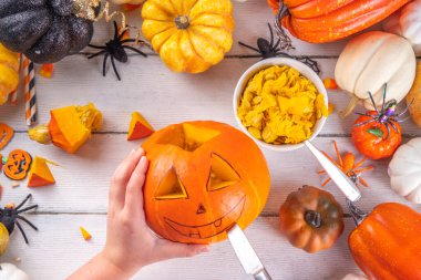 Balkabağı oyma Jack Feneri ile Cadılar Bayramı hazırlığı. Kadın, kadın ve çocuklar ellerini çerçeveye koyar, dekore eder, çizer ve korkunç Cadılar Bayramı partisini oyar.