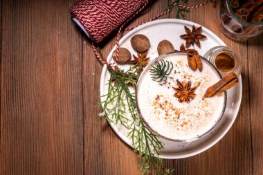 Yeni yıl Noel kreması baharatlı kokteyl eggnog, Cola de-mono. Sütlü, yumurtalı, romlu, tarçınlı ve hindistan cevizli sıcak kış içeceği ahşap arka planda Noel süsüyle