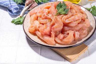 Diyet beyaz kümes hayvanlarını pişirmek. Taze dilimlenmiş tavuk şeritleri pişirmek için, baharatlar, otlar, beyaz fayansların arka planında fotokopi alanı