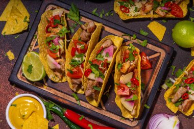 Traditional Mexican street food, fast food background, corn Taco, nachos with meat, vegetables, avocado, beans, corn, salsa. Served with various sauces. Mexican holiday flatlay