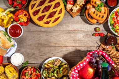 Çeşitli piknik barbekü yemekleri ve flatlay içiyorlar. Yaz bbq piknik yemekleri, ızgara etler, kebaplar, sebzeler, meyve salatası, geleneksel piknik pastası, sandviçler, üst görünüm fotokopi alanı.