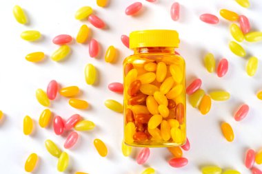 Jelibon ve yetişkinler için vitamin takviyesi. Kadın, şeffaf ilaç şişesinden, modern ilaçlardan ve takviye malzemelerden tatlı multivitamin şekerleri yer. 