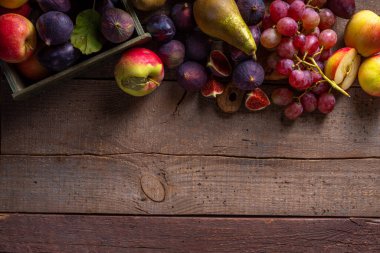 Sonbahar meyve çeşitleri. Sonbahar hasadı mevsimlik meyve ve meyveler - erik, elma, incir, armut, üzüm, ahşap masa fotokopi alanı üzerinde