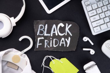 Satış etiketleri, giysileri, dizüstü bilgisayarı, kulaklıkları, akıllı telefonu, tableti, satış maddeleri, düz görünüm kopyalama alanı olan Kara Cuma satış arkaplanı