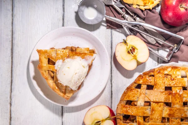 Traditional autumn apple pie. Sweet Thanksgiving dinner, fall seasonal cake with apples, cinnamon, nuts and caramel, with vanilla ice cream scoop ball, on wooden cosy background