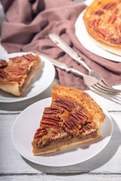 Traditional autumn pecan pie, American Thanksgiving holiday cake with pecans, maple syrup,  on wooden cosy background