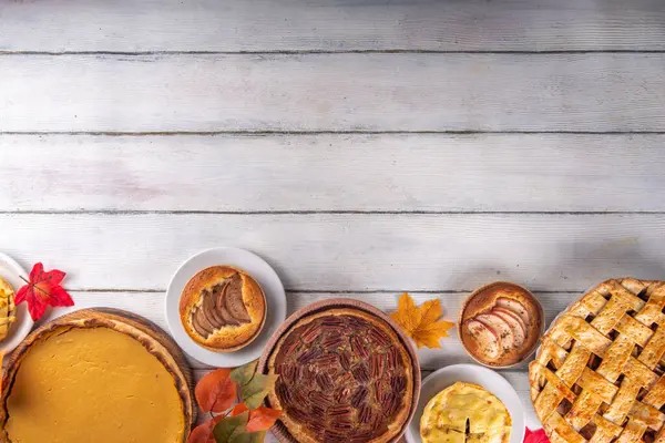 Assorted homemade fall cakes. Traditional autumn american european pumpkin, apple and pecan pie. Thanksgiving family dinner, seasonal homemade baking and pastry background on wooden table