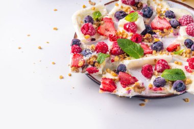 Ev yapımı donmuş yoğurt kabuğu, Yunan yoğurdundan yapılan alternatif sağlıklı keto diyeti dondurması, taze böğürtlen, fındık, granola, bal, fırın tepsisi deco. Meyve soslu donmuş yoğurt.