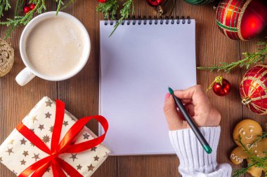 Noel, yeni yıl kış tatili hazırlığı, boş not defteri, kırmızı kurdeleli hediye kutusu, latte ya da kakao fincanı, köknar ağacı dalları ve Noel mücevherleri, kopya alanı.
