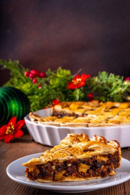 Geleneksel İngiliz Noel turtası. Ev yapımı tatlı kıymalı tart kek, baharatlı meyve, fındık ve elmalarla dolu, rahat ahşap masa üzerinde Noel ağacı ve süslemesi ile
