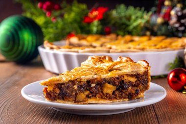 Geleneksel İngiliz Noel turtası. Ev yapımı tatlı kıymalı tart kek, baharatlı meyve, fındık ve elmalarla dolu, rahat ahşap masa üzerinde Noel ağacı ve süslemesi ile