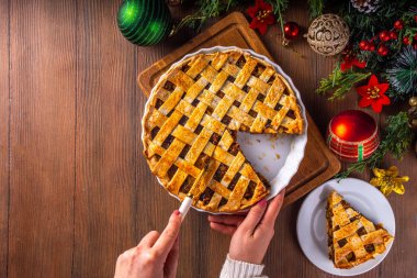 Geleneksel İngiliz Noel turtası. Ev yapımı tatlı kıymalı tart kek, baharatlı meyve, fındık ve elmalarla dolu, rahat ahşap masa üzerinde Noel ağacı ve süslemesi ile