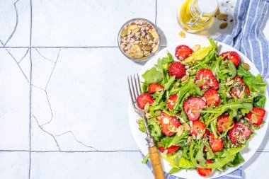 Yaz sağlıklı yemekleri, çilekli roka salatası. Taze diyet çilek salatası roka, ıspanak, marul, çeşitli fındık ve tohumlar, beyaz fayans arka planında fotokopi alanı