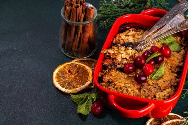 Kış ev yapımı glütensiz yulafsız yulaflı tart. Tatlı, lezzetli yaban mersinli yulaf ezmesi, çıtır kek. Noel pastası tarifi fikri, koyu yeşil masa arkaplanı