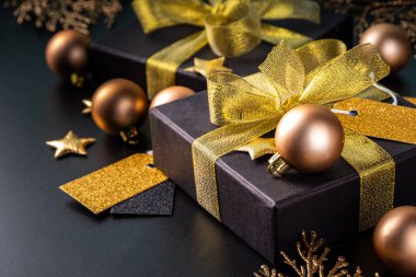 Mutlu Noeller, mutlu bayramlar tebrik kartı geçmişi, yeni yıl, Noel, kış xmas tatilleri düzlüğü. Noel altın süsleri, dekor köknar ağacı, siyah arkaplandaki hediye kutuları, fotokopi alanı