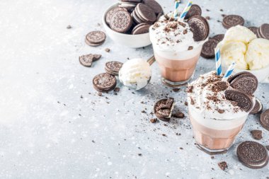 Kahve, sütlü ve kurabiyeli milkshake. Dondurma ve çikolatalı kurabiyeler tatlı latte kokteyli. Kaşık ve vanilyalı dondurmayla birlikte gri beton masada. Boşluğu kopyala
