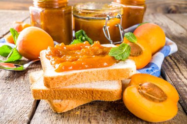 Farklı kavanozlarda ev yapımı kayısı reçeli, ahşap arka planda taze organik kayısılar fotokopi alanı