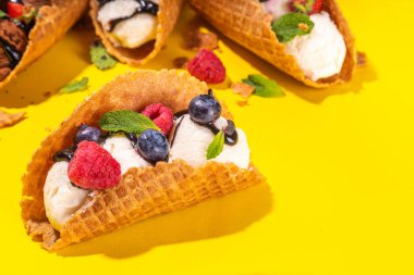 Çeşitli tatlı taco dondurmaları. Çikolata ve vanilya aromalı waffle kabukları. Farklı meyveler, meyveler, malzemeler.