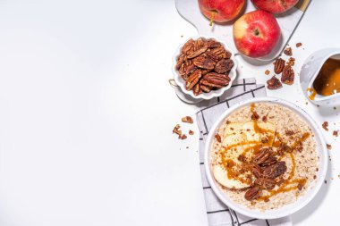 Basit bir sonbahar geleneksel Amerikan kahvaltısı. Elmalı yulaflı yulaf lapası, elmalı, cevizli ve karamelli beyaz masa arkası fotokopi masası.