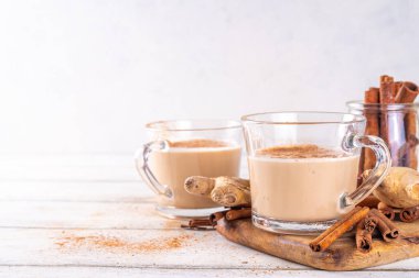 Tarçın üzümlü boğaz çayı sütlü, zencefilli ve hindistan cevizli süt, beyaz ahşap mutfak masasında, kopyalama alanı