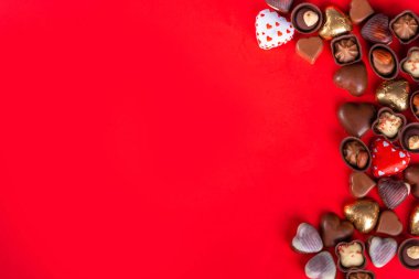 Valentines Day chocolates banner, background, frame. Various sweets and chocolate candy on red paper background with copy space. Romantic composition. Happy Valentine's day greeting card background