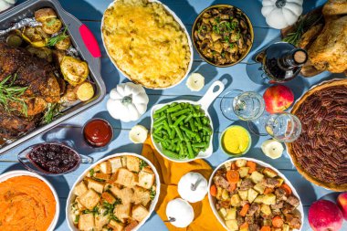 Thanksgiving dinner table with new traditional thanksgiving food - chicken, mashed sweet potatoes, green beans, pecan pie, baked ham pork, mac and cheese, stuffing, modern hard sunny light flatlay clipart